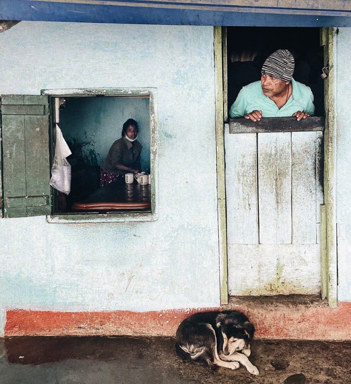 Man with dog curled up in front of a house in Sri Lanka